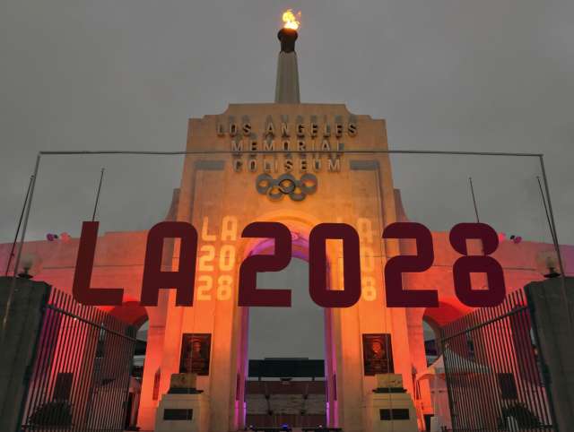 FILE - An LA 2028 sign is seen in front of the Olympic cauldron at the Los Angeles Memorial Coliseum, Wednesday, Sept. 13, 2017. As the Olympics close in Paris, Los Angeles will take the torch. The city will become the third city to host the games three times as it adds 2028 to the locally legendary years of 1932 and 1984. (AP Photo/Richard Vogel, File)